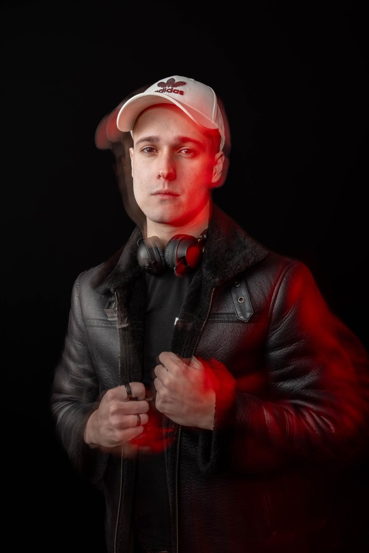 Retrato de DJ Robles con gorra y chaqueta bajo luz roja