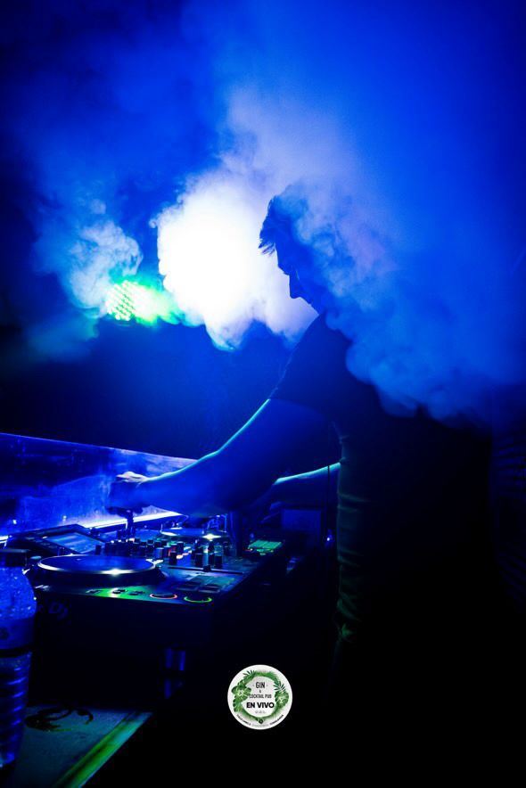Cabina de DJ entre humo y luces azules en una sesión de club